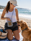 Woman wearing a handmade crochet Bone Appétit Pup dog treat pouch while spending time with her dog at the beach
